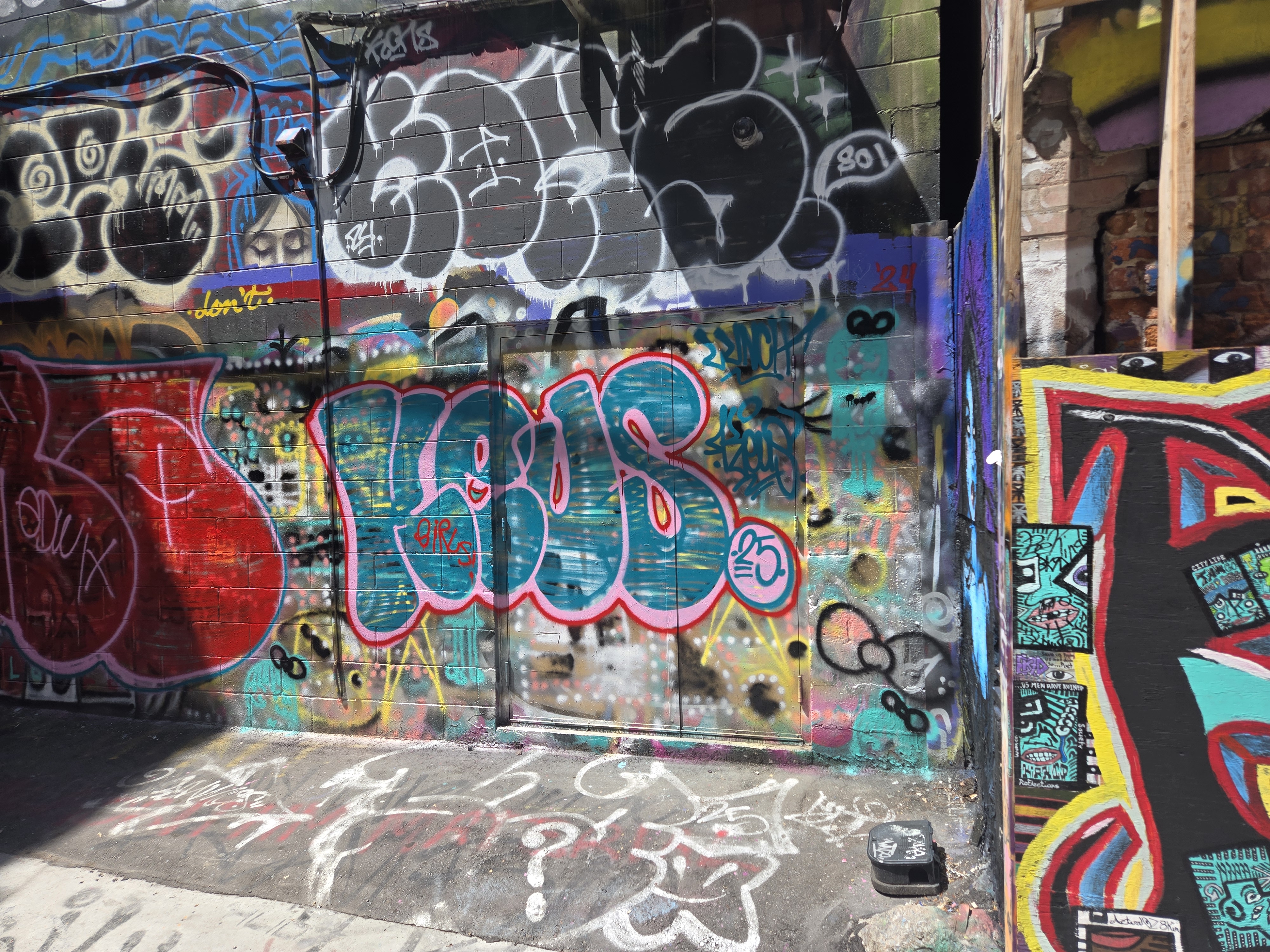 A Kensington laneway wall covered in overlapping graffiti throw-ups and tags.